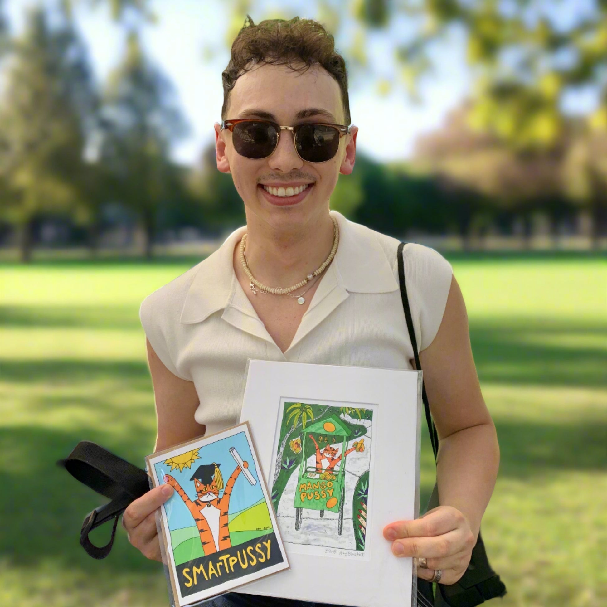 a person holding an art print  and graduation card featuring Superpussy